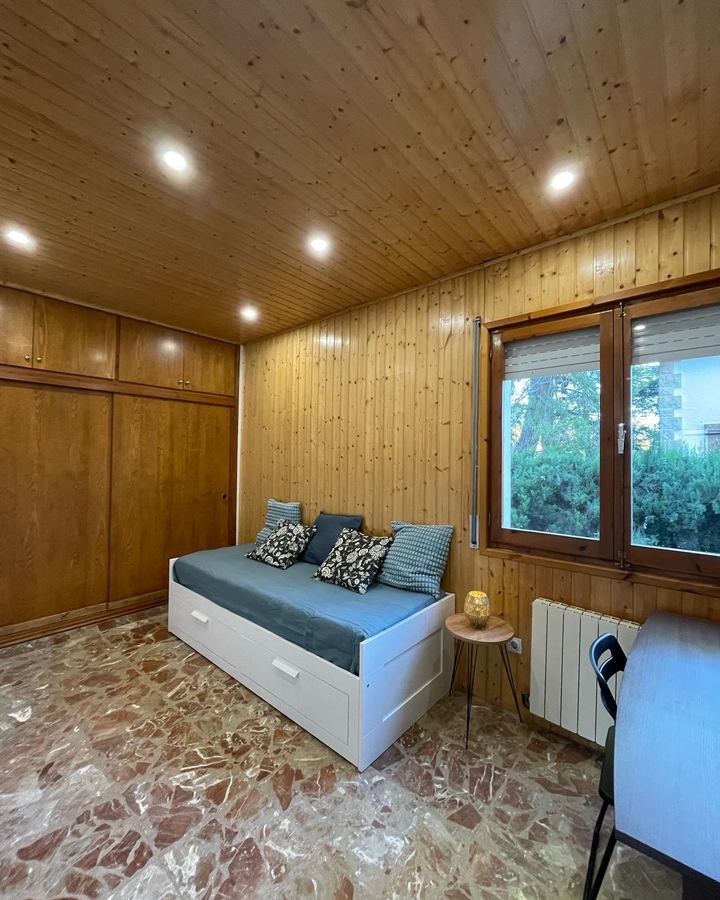 Habitación con cama nido y pared de madera